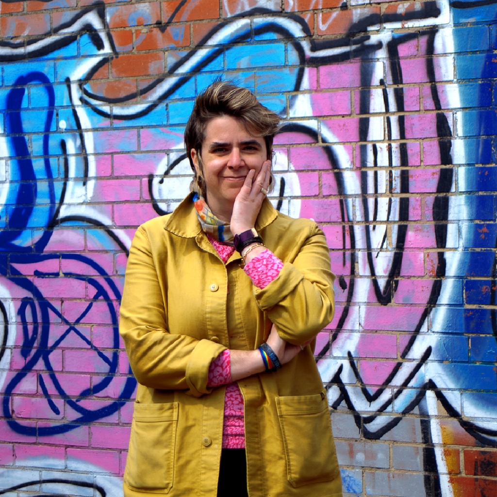 Image of the business owner, Samantha, standing in front of a wall smiling and looking forwards